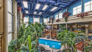 A spacious indoor atrium with a central pool, multiple levels, and abundant greenery. - L'Hôtel Québec par JARO (Québec City)