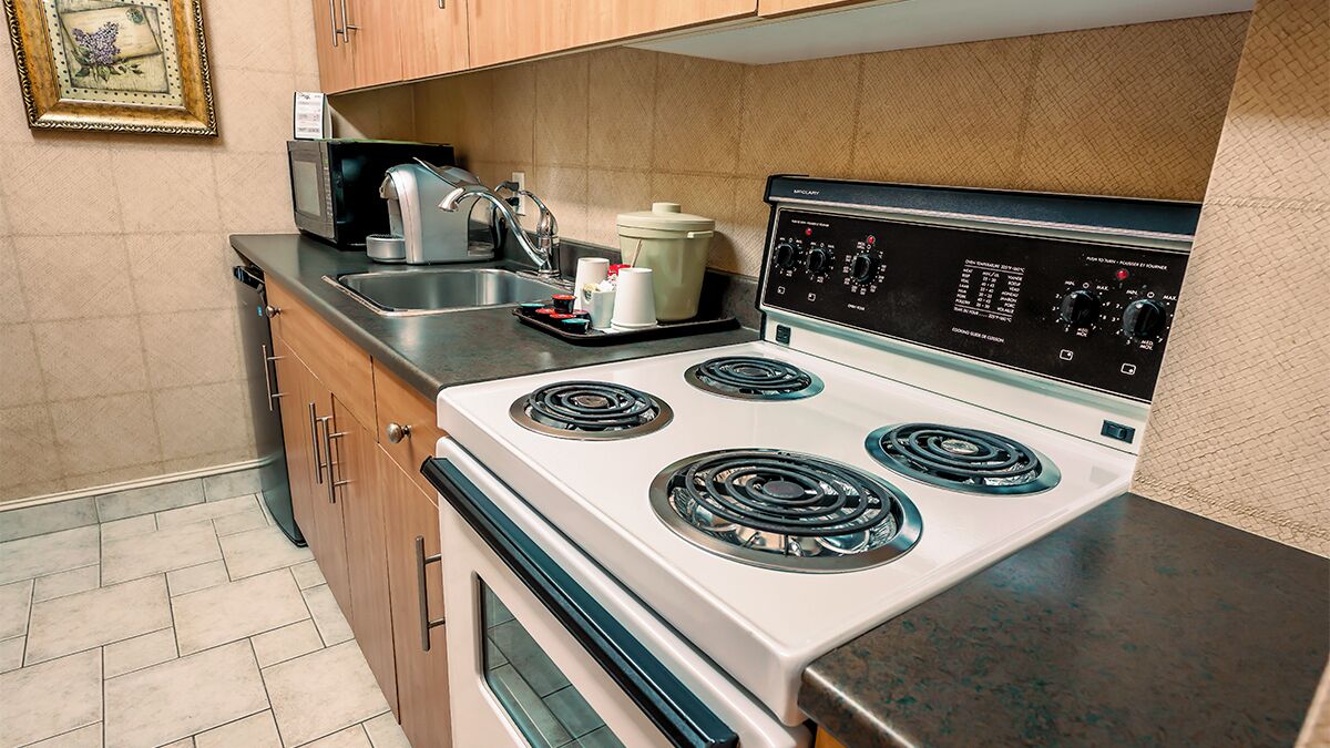 A compact kitchen with a white stove, a microwave, and a sink.