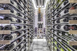 A wine cellar with rows of wine bottles on shelves. - L'Hôtel Québec par JARO (Québec City)