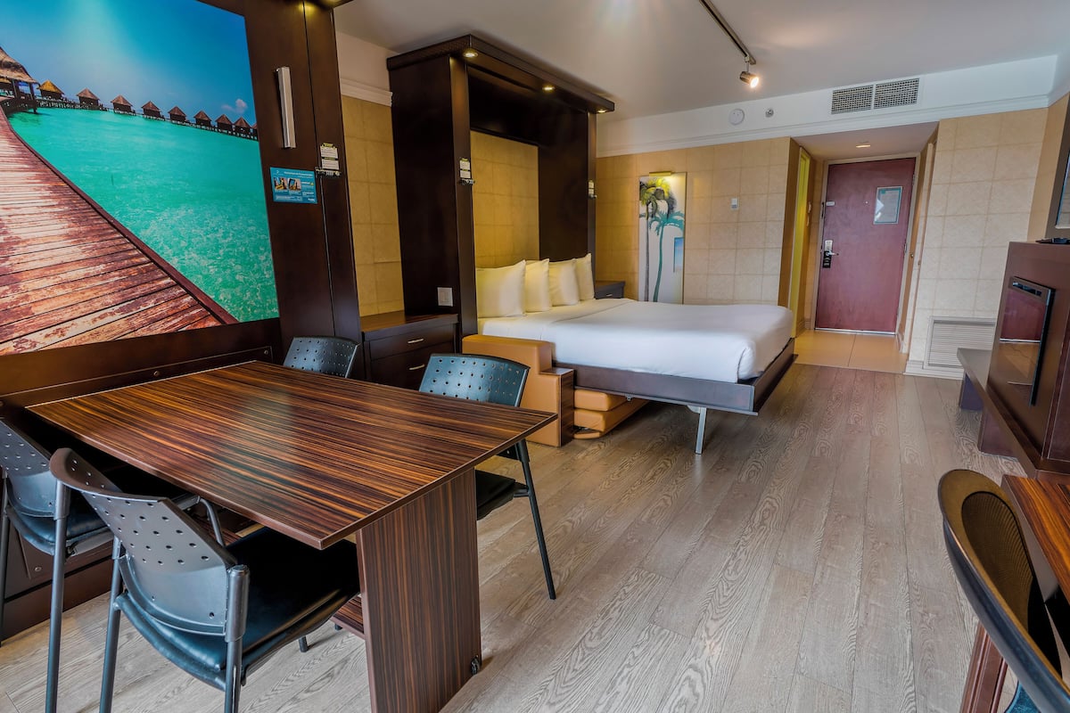 A hotel room with a bed, a desk, and a chair.