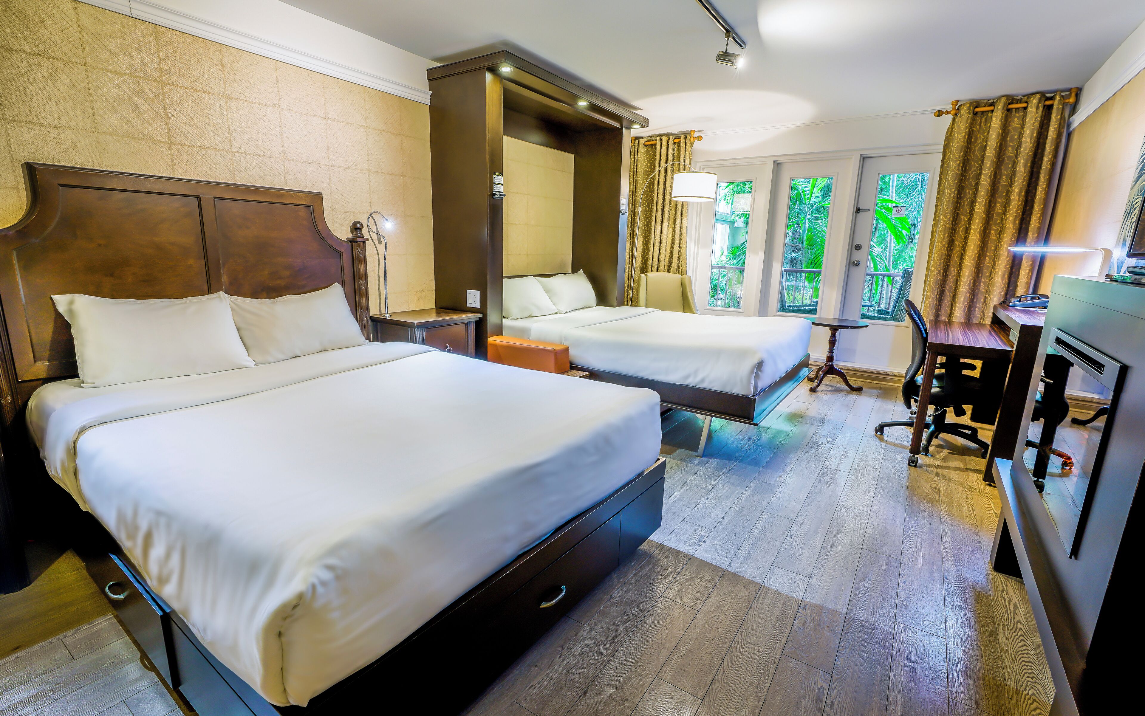 A hotel room with two beds, a desk, and a chair.