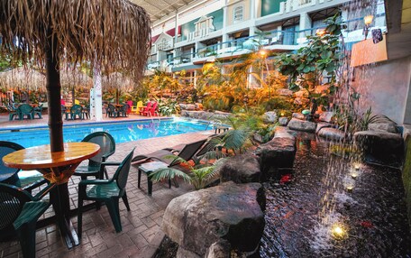 An indoor pool area with lounge chairs, a table, and a waterfall feature.