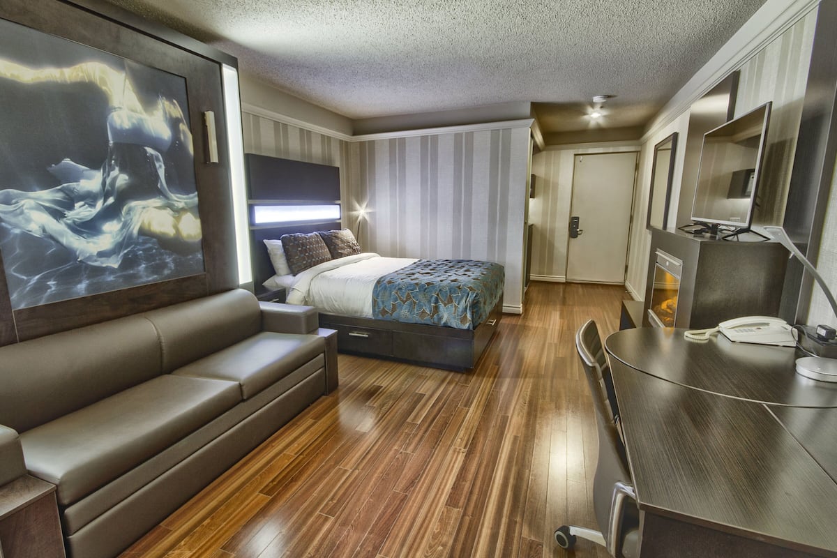 A modern bedroom with a large bed, a sofa, a desk, and a television.