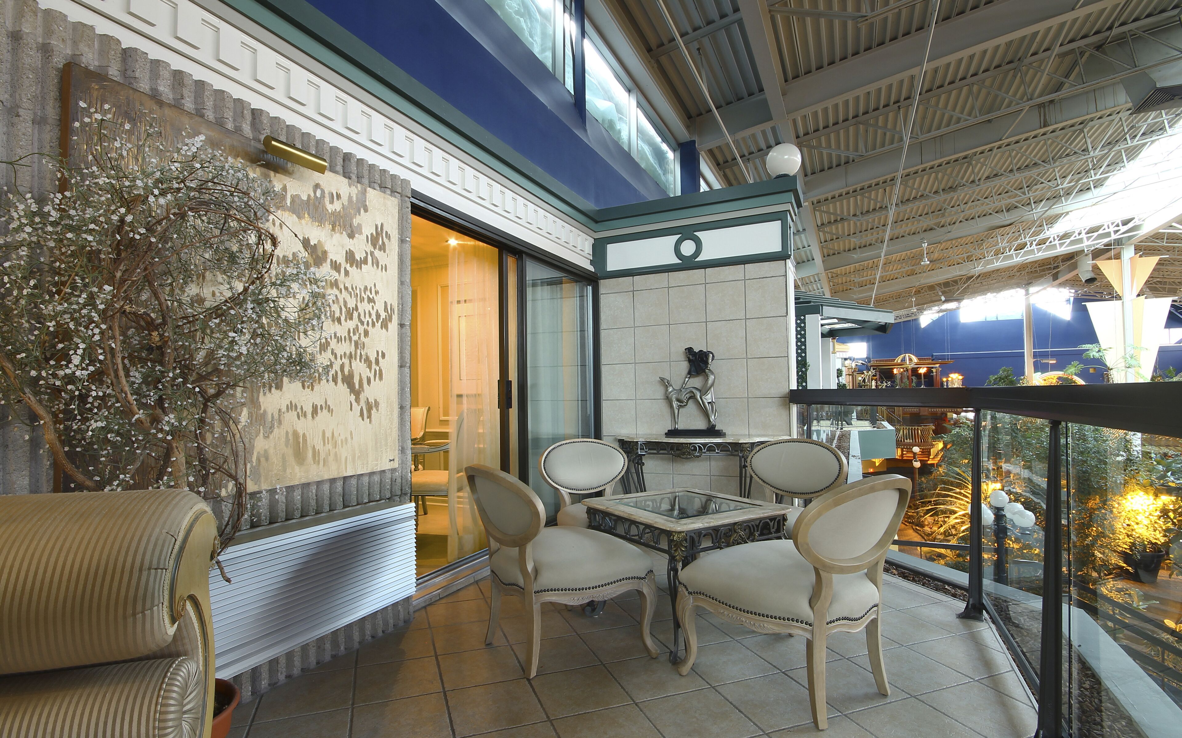 Un balcon avec une table et des chaises, un mur décoratif et une vue sur l’intérieur.