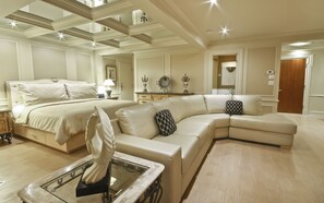 A spacious hotel room with a large bed, a sofa, and a glass coffee table.