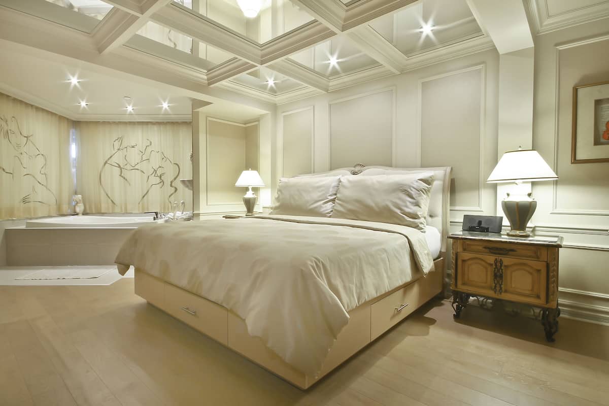 A spacious bedroom with a large bed, a vanity with a mirror, and a nightstand with a lamp.