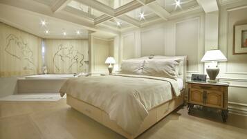 A spacious bedroom with a large bed, a vanity with a mirror, and a nightstand with a lamp.