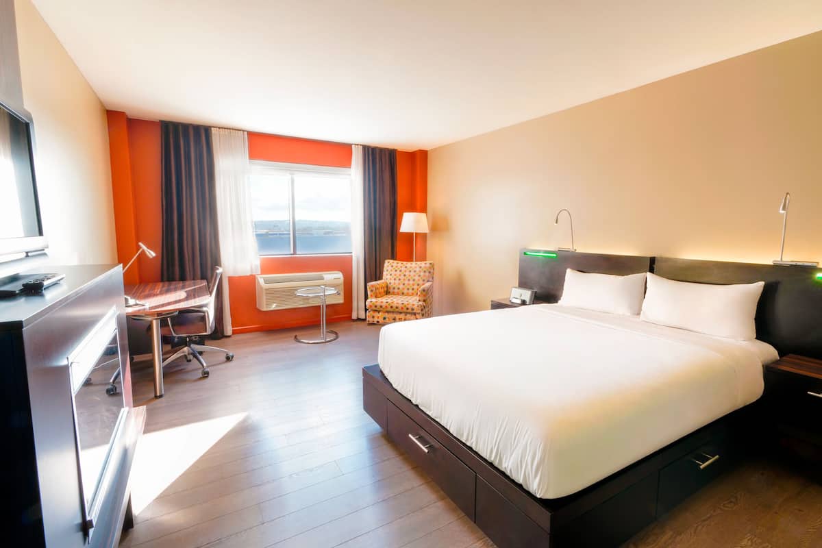 Habitación de hotel con cama, escritorio, silla y vistas a la ciudad.