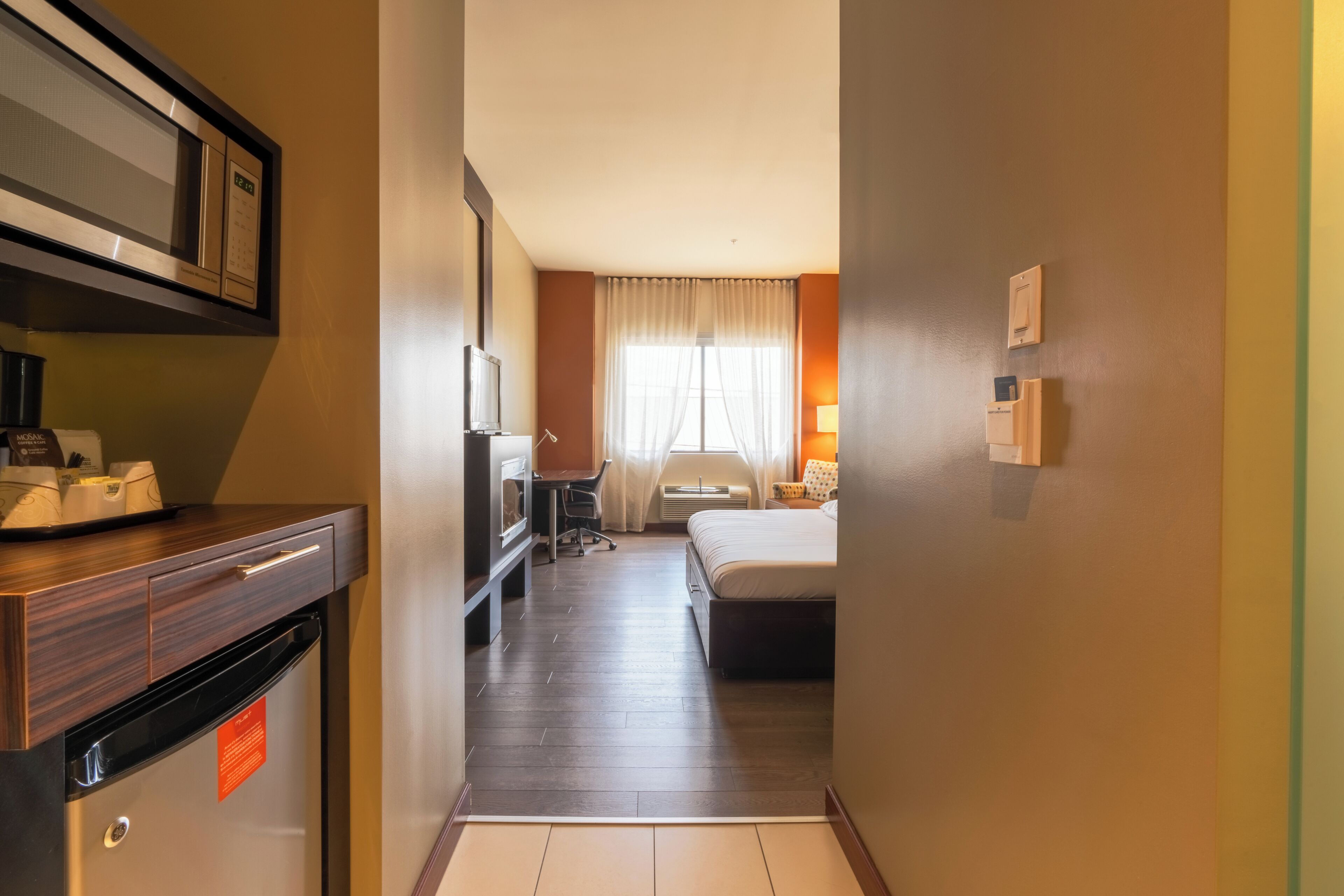 Une chambre d’hôtel équipée d’un lit, d’un bureau, d’une chaise, d’une télévision et d’un mini-bar.