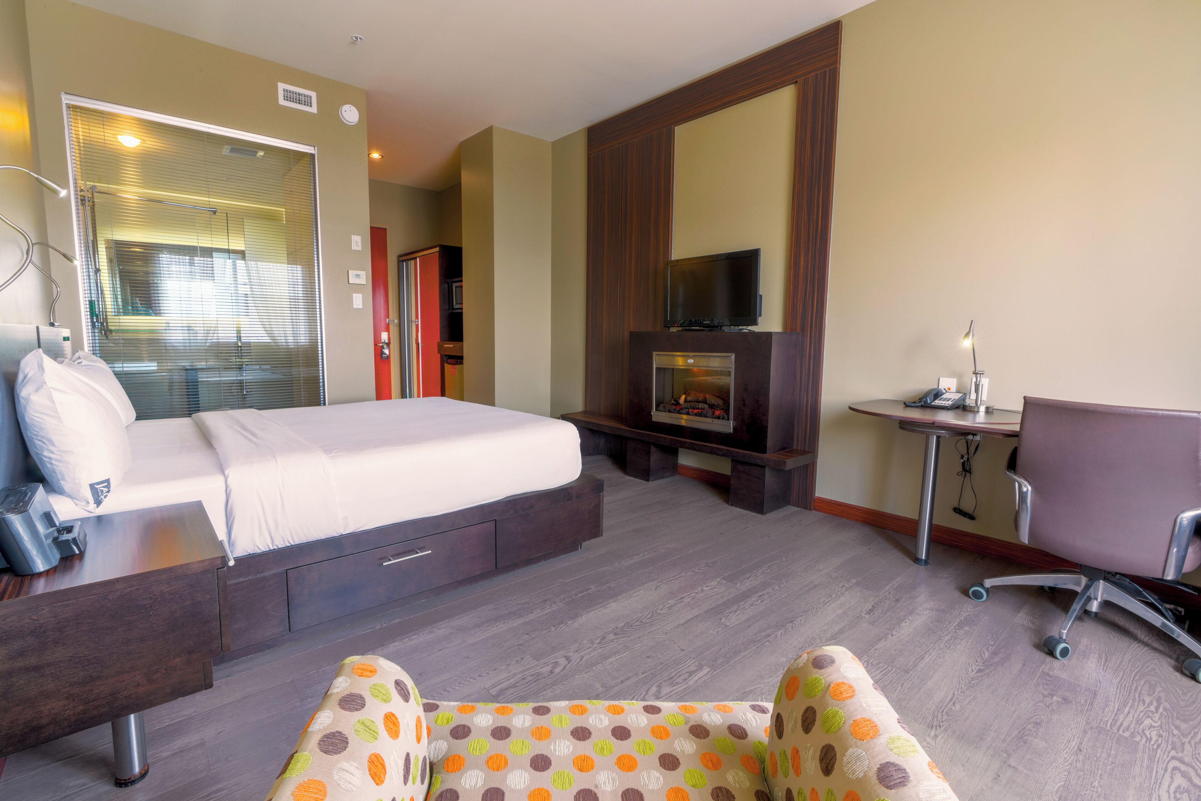 Una habitación de hotel con una cama, un escritorio, una silla, un televisor y una chimenea.