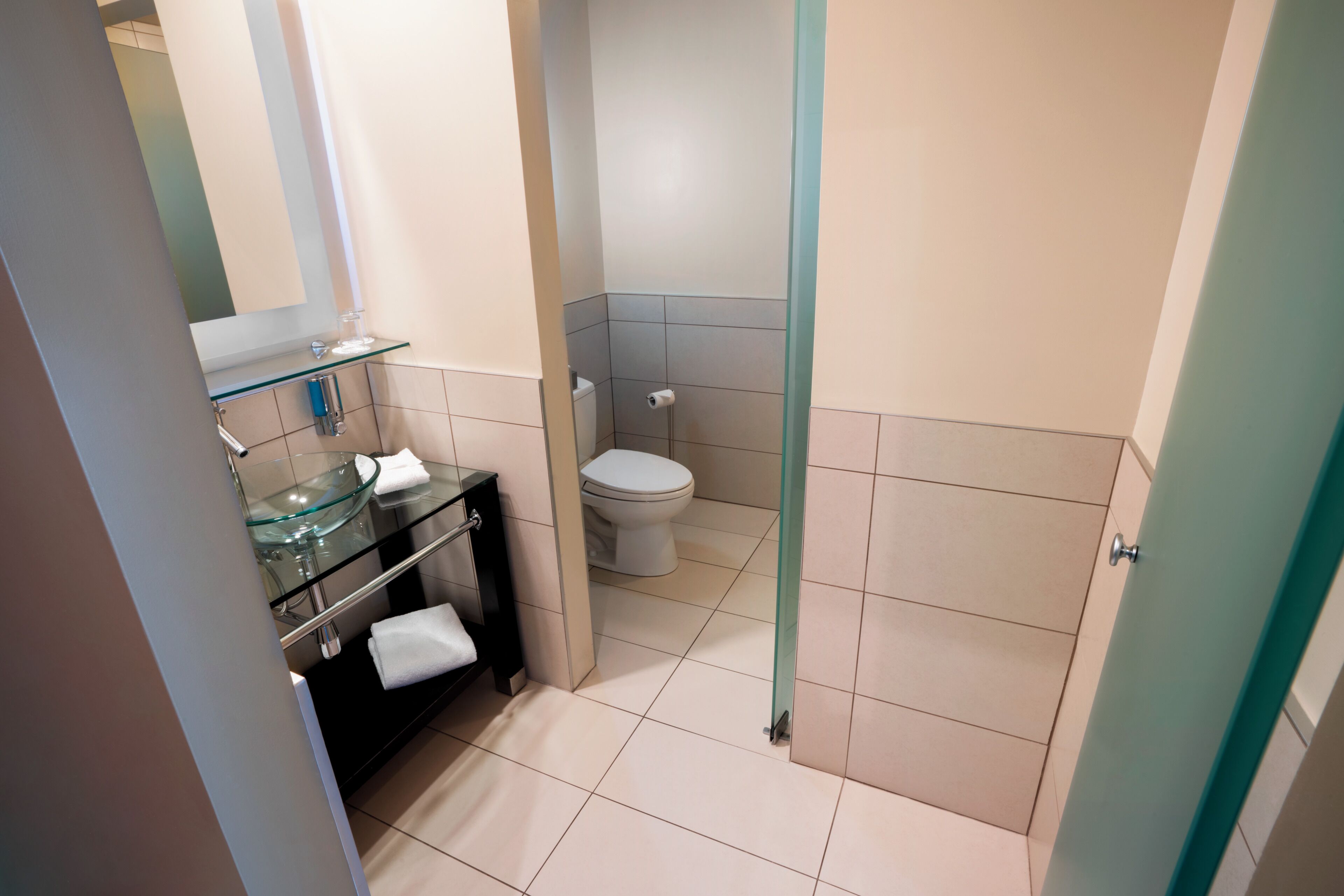 Ein Badezimmer mit einem Glaswaschbecken, einer Toilette und einer Duschkabinentür aus Glas.