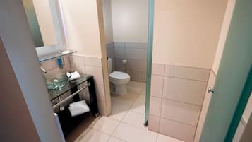 Une salle de bain avec un lavabo en verre, des toilettes et une porte de douche en verre.