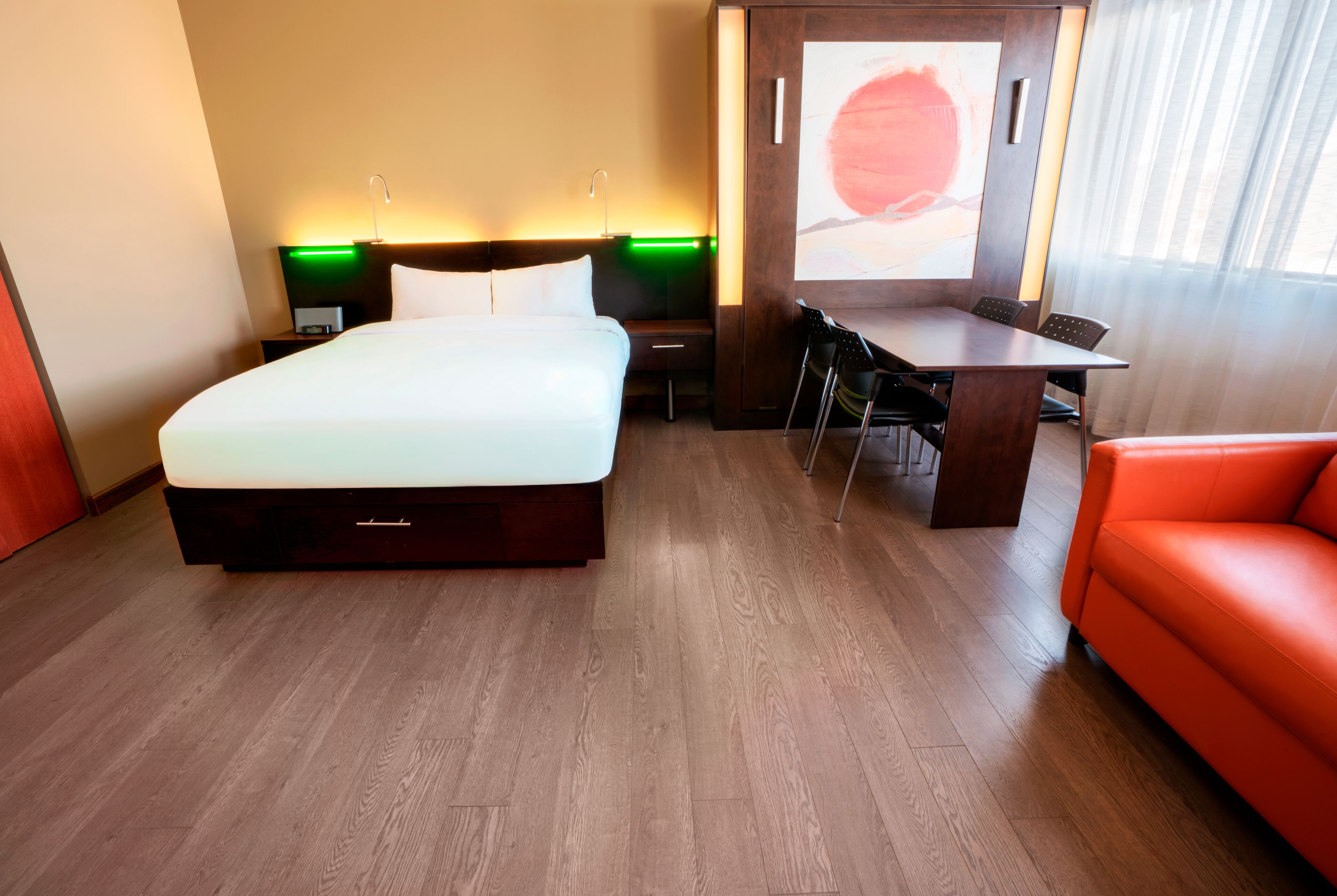 Une chambre d’hôtel avec un lit, un bureau, des chaises et un canapé rouge.