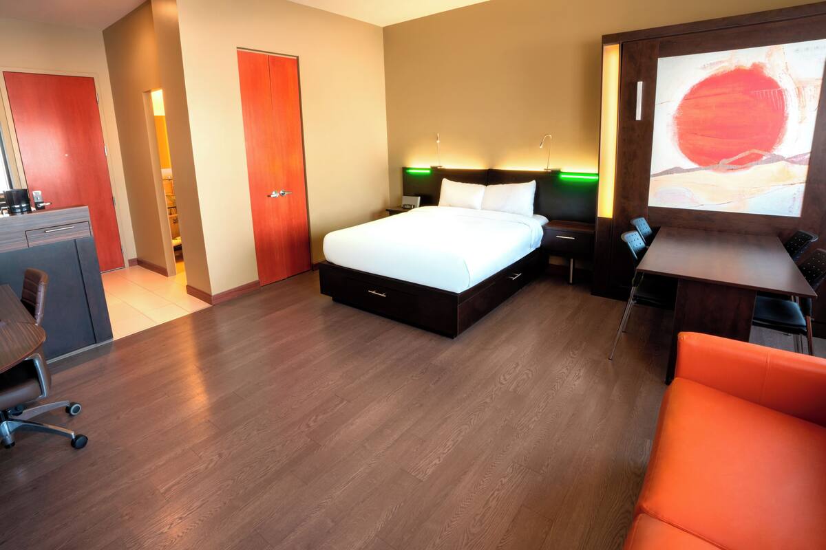 Habitación de hotel con cama, escritorio, silla y televisor.