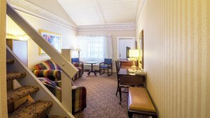 Quarto de hotel com escada, sofá, mesa de jantar e uma cadeira.
