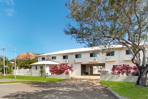 Un motel de dos pisos con fachada blanca, un acceso cubierto y un letrero que indica 'Castle Crest Motel'.