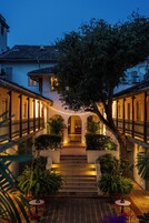 A courtyard with a central staircase, surrounded by buildings with balconies and string lights.