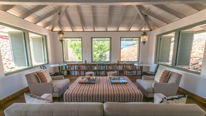 A cozy reading room with a large sofa, a coffee table, and a bookshelf filled with books.