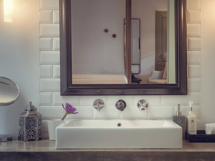 A bathroom with a white sink, a large mirror, and a dark wooden cabinet.
