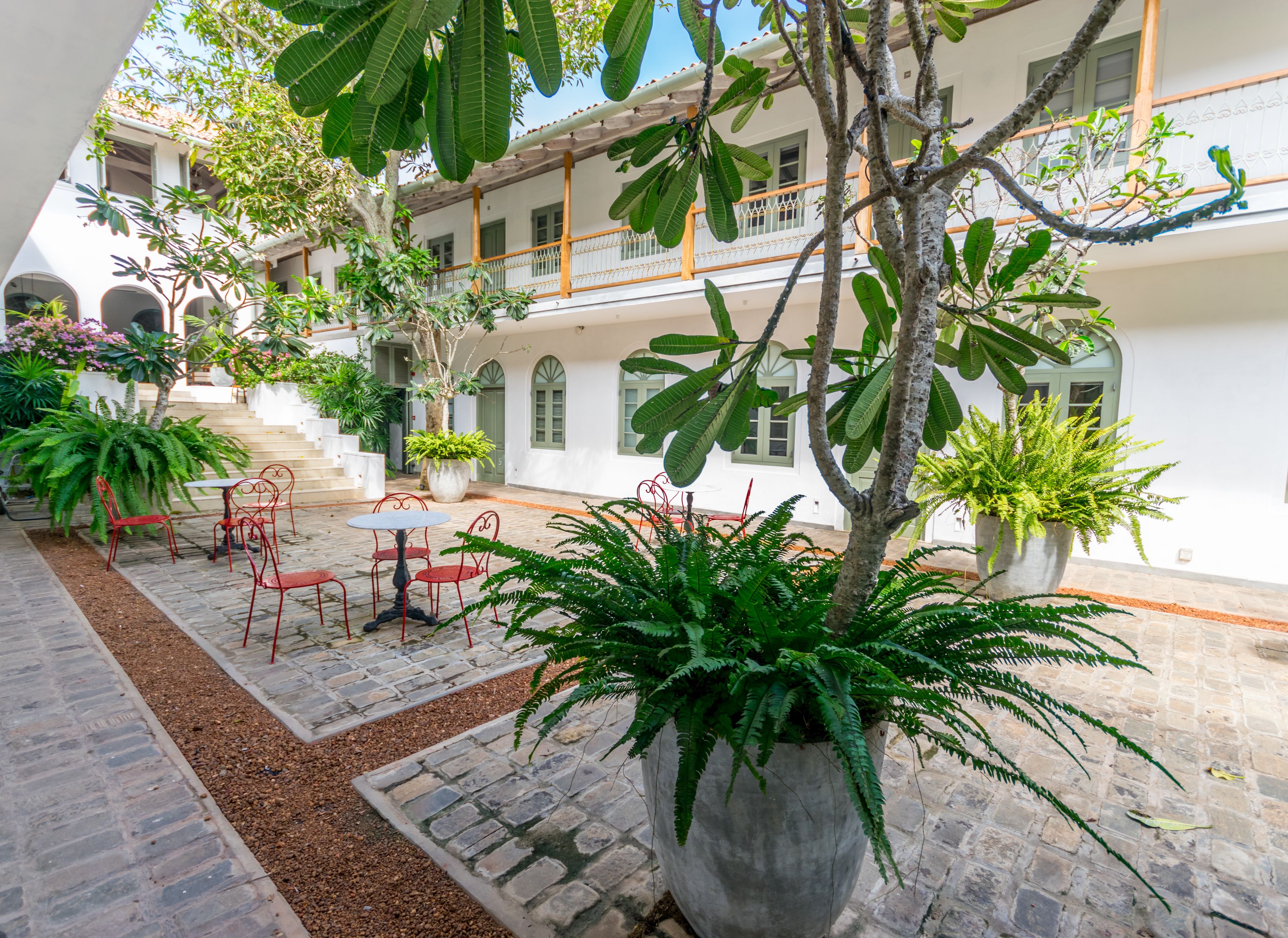 A courtyard with a stone floor, potted plants, and outdoor seating.
