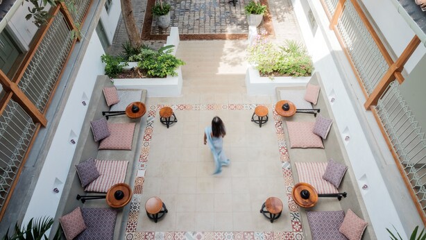 Un patio con mobiliario exterior, plantas en macetas y suelo de baldosas.