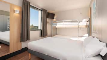 Et moderne hotelværelse med køjeseng, dobbeltseng, tv og et vindue med gardiner.