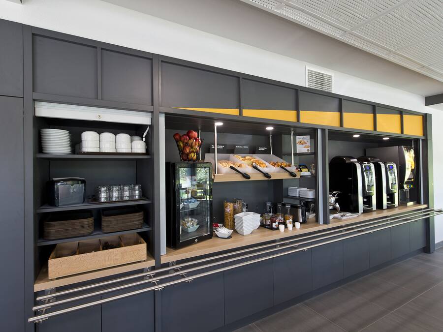 Una estación de desayuno autoservicio con diferentes alimentos, salsas y una máquina de café.