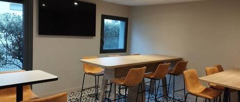 A conference room with a large table and chairs, a projector screen, and a window with a view of trees.