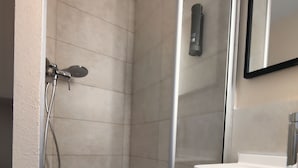 A shower with a glass door, a white sink, and a mirror above the sink. - B&B HOTEL La Rochelle Centre les Minimes (La Rochelle)