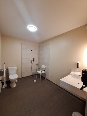 A small bathroom with a toilet, a shower, and a sink.