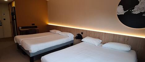 A hotel room with three beds, a wooden headboard, a wall map, and a door.