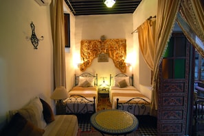 A room with two beds, a small table, and a patterned rug. - Dar Hafsa (Fes)
