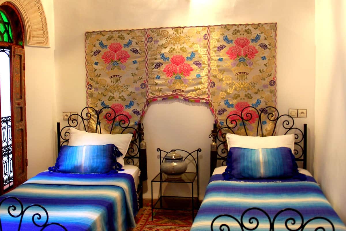 Quarto com duas camas, tapeçaria estampada e porta decorativa.