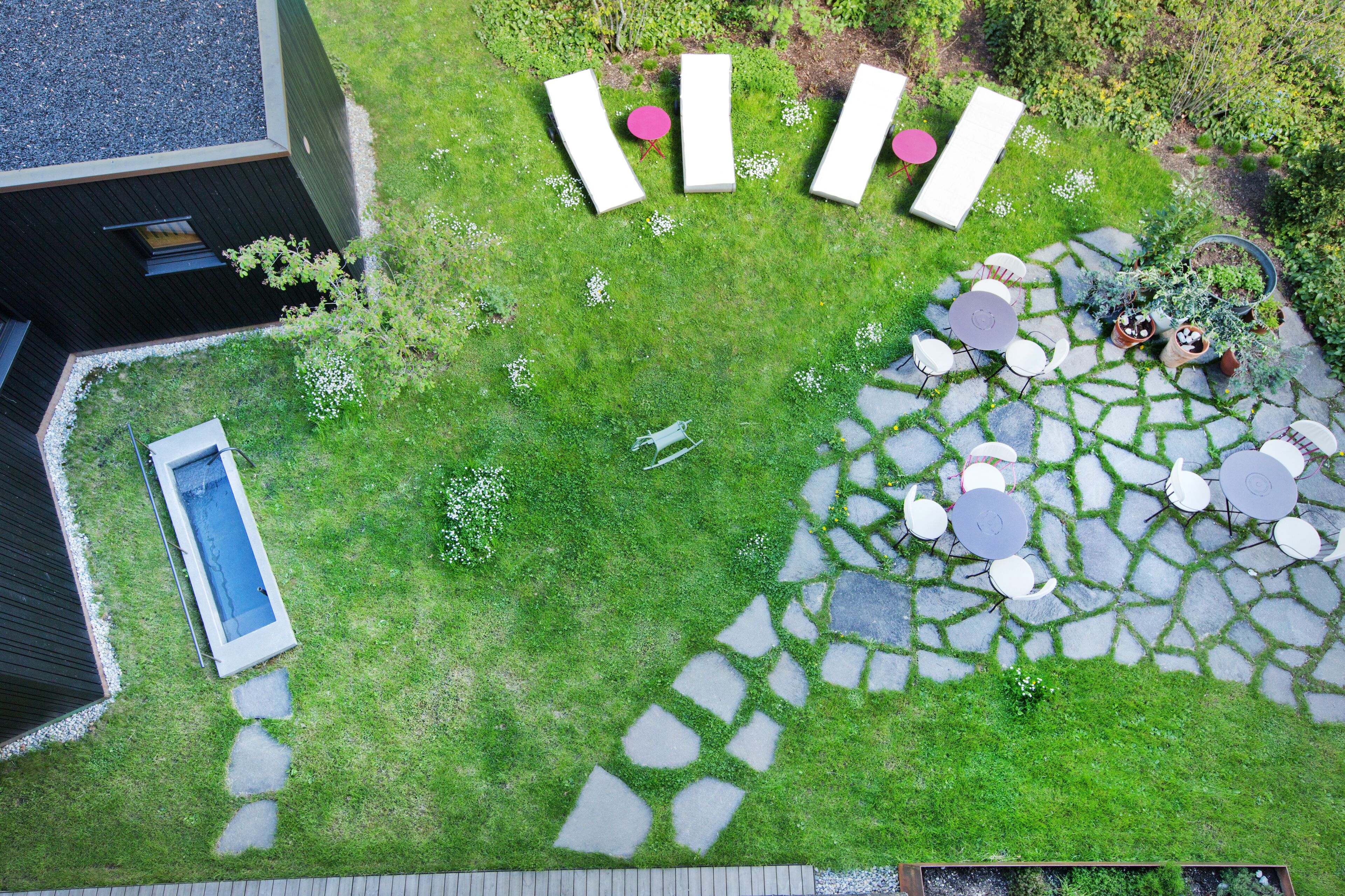 Un jardín con piscina, sendero de piedra y zona de estar al aire libre.