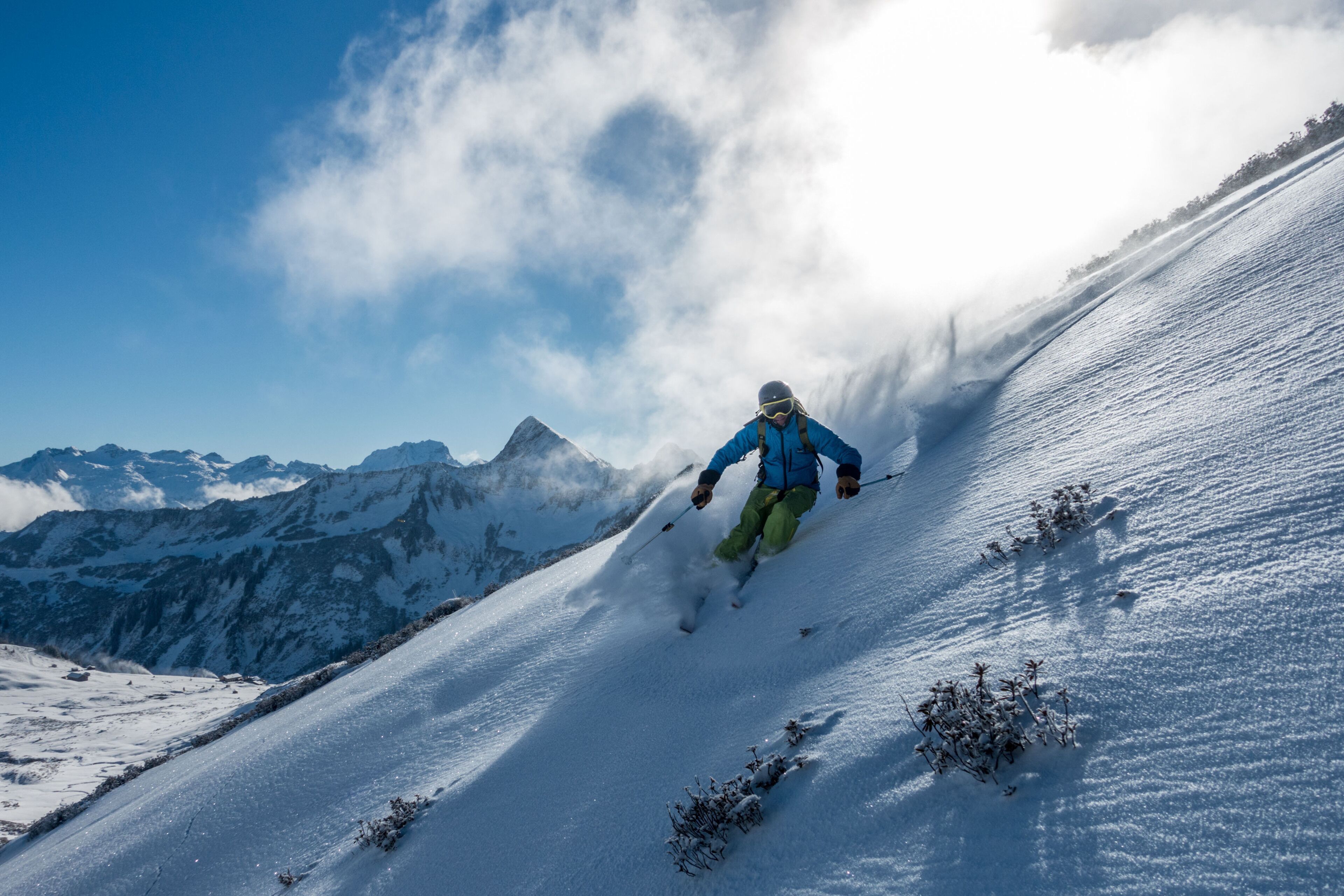 A skier on a snowy slope with mountains in the background.