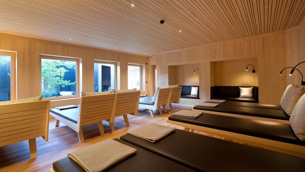 A room with wooden panel walls, large windows, and multiple massage tables with cushions. -  Krone Hittisau - Hotel & Restaurant im Bregenzerwald (Hittisau)