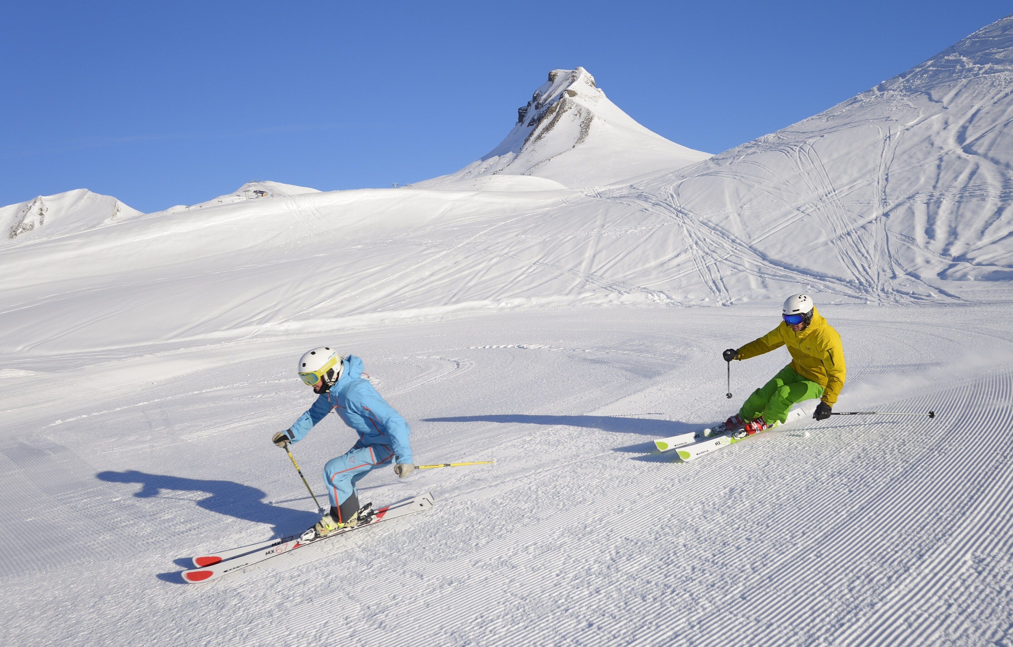 A snowy ski slope with two skiers.
