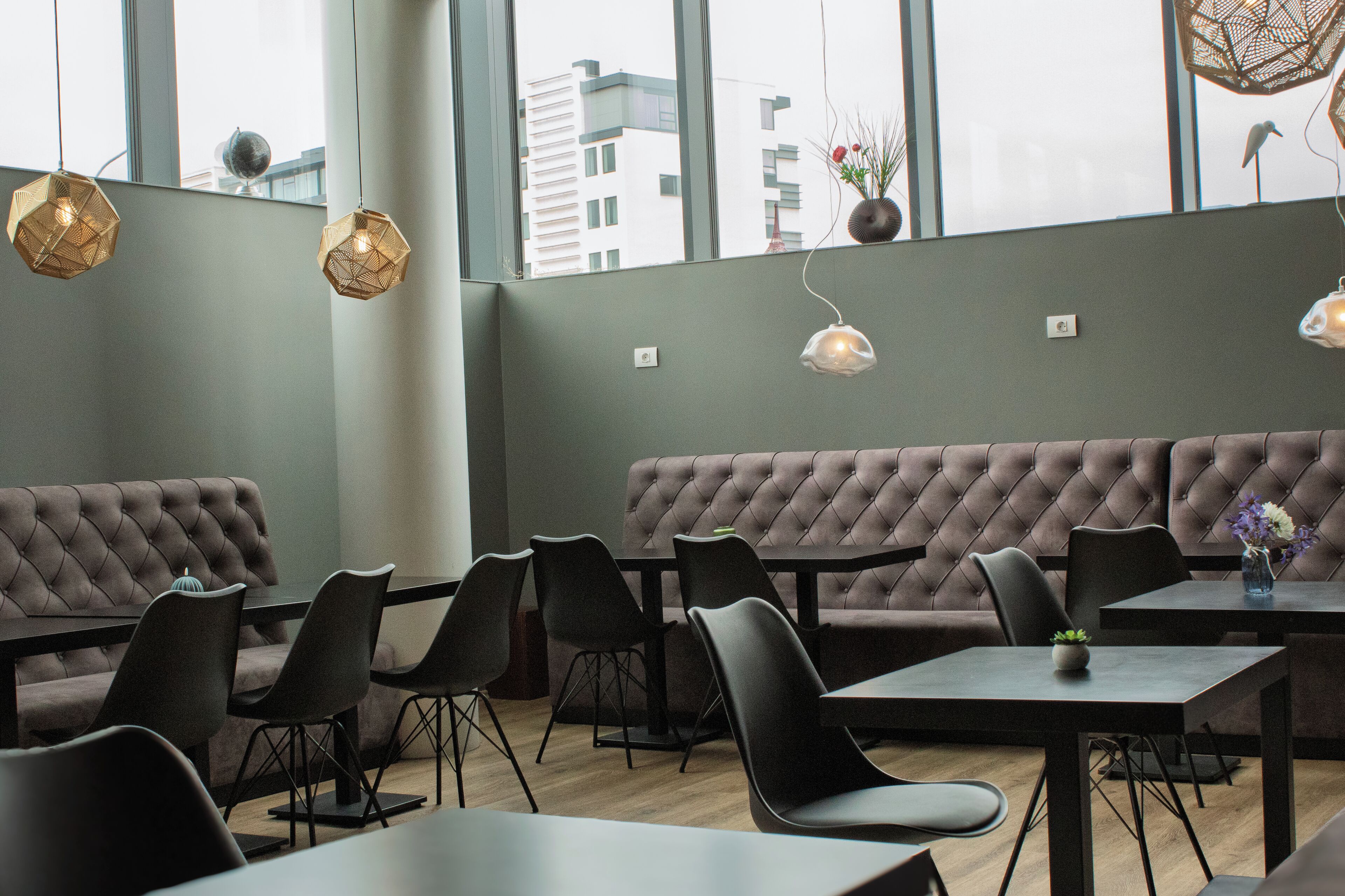 Un comedor moderno con un amplio banco acolchado, varias mesas y sillas.