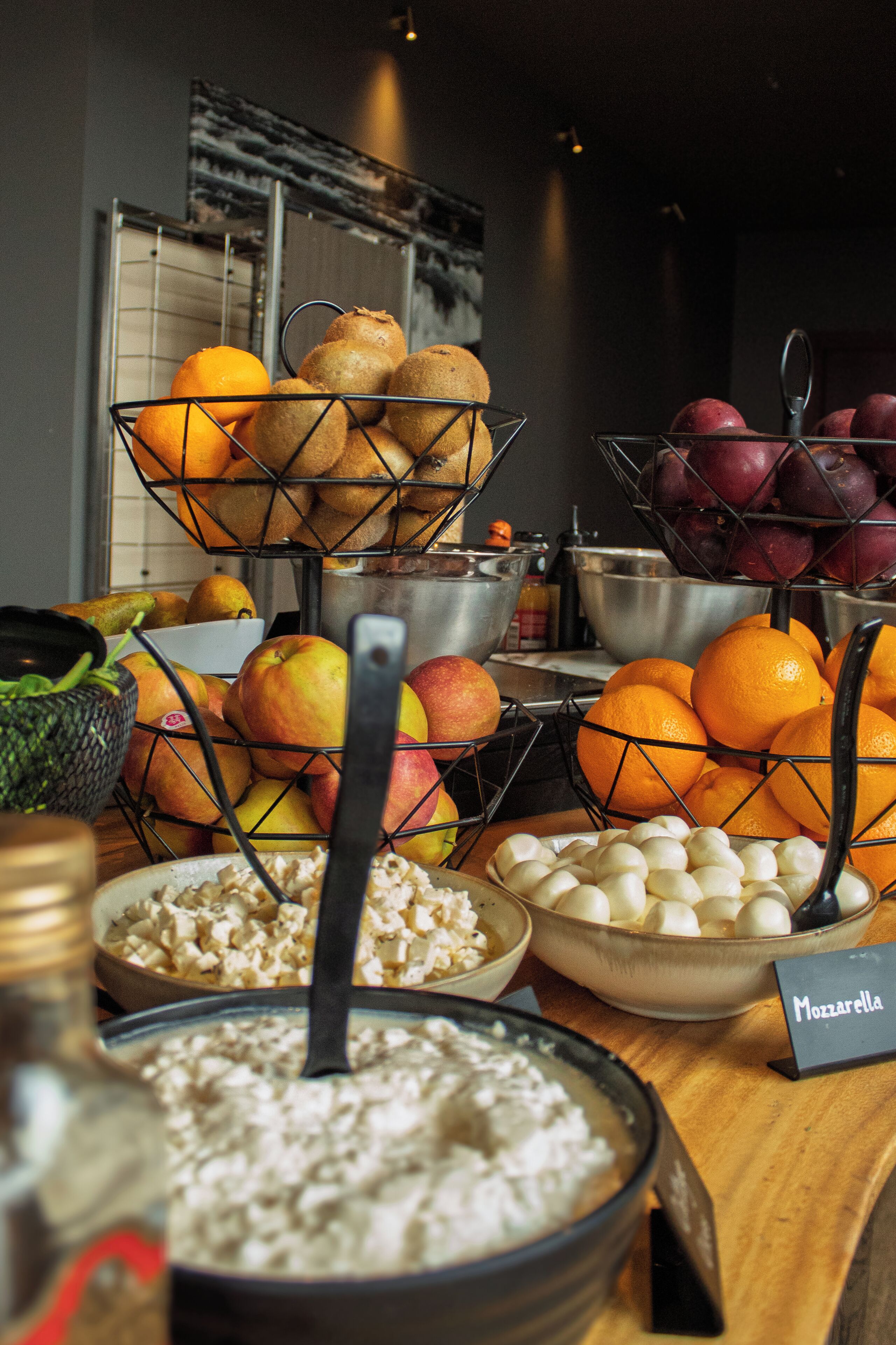 A buffet table with various food items including fruits, vegetables, and a bowl of cereal.