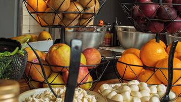 A buffet table with various food items including fruits, vegetables, and a bowl of cereal.