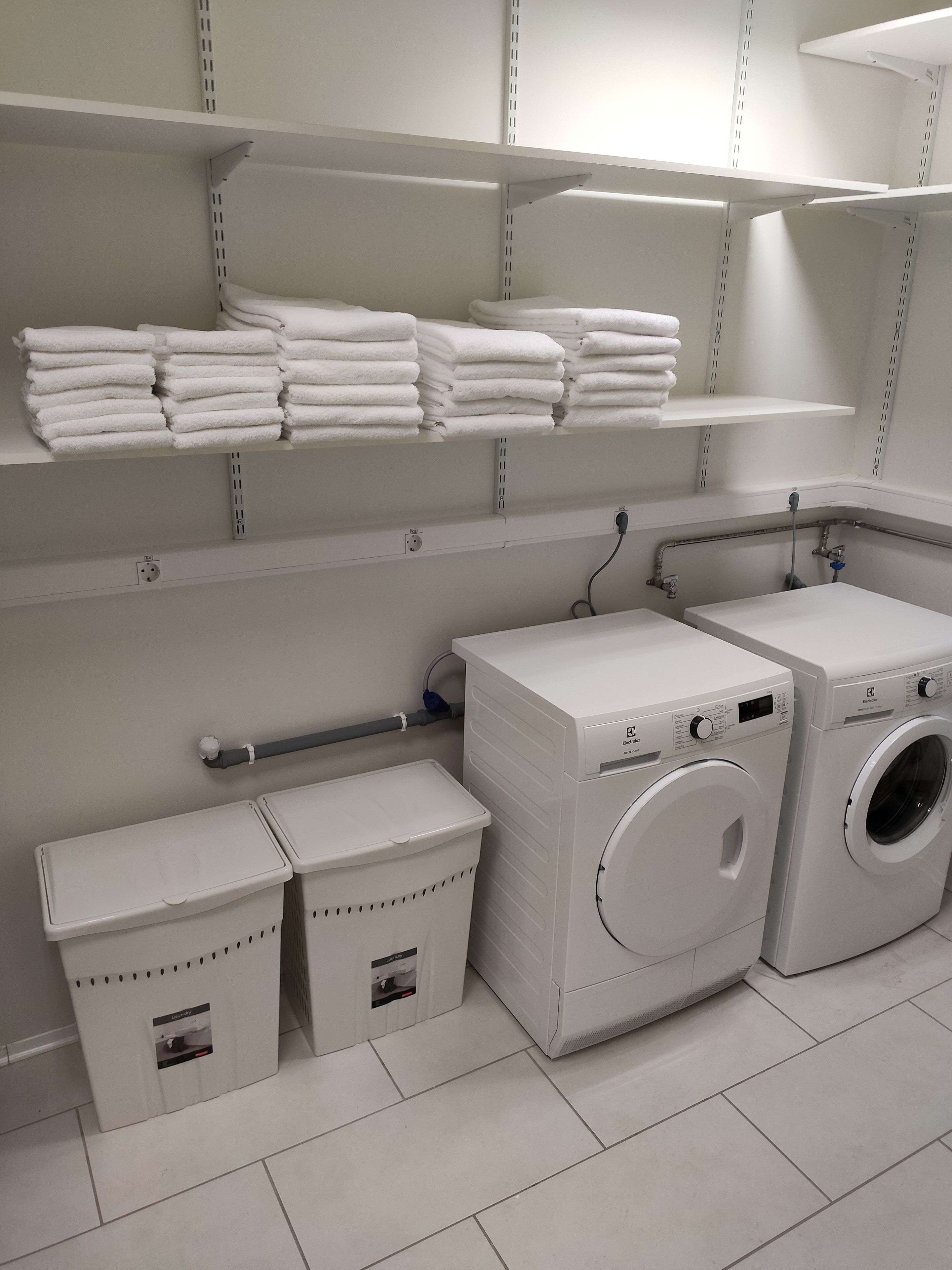 Un espace buanderie avec des piles de serviettes rangées sur des étag ères, un lave-linge et un sèche-linge.