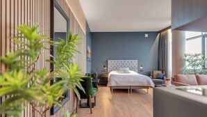 A modern bedroom with a large bed, a seating area, and a view of the outdoors. - Hótel Múli (Reykjavik)