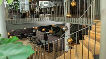 A multi-level interior with a staircase, seating areas, and pendant lighting.