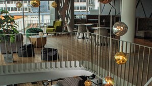 A modern interior with a spiral staircase, wooden flooring, and a seating area with tables and chairs. - Hótel Múli (Reykjavik)