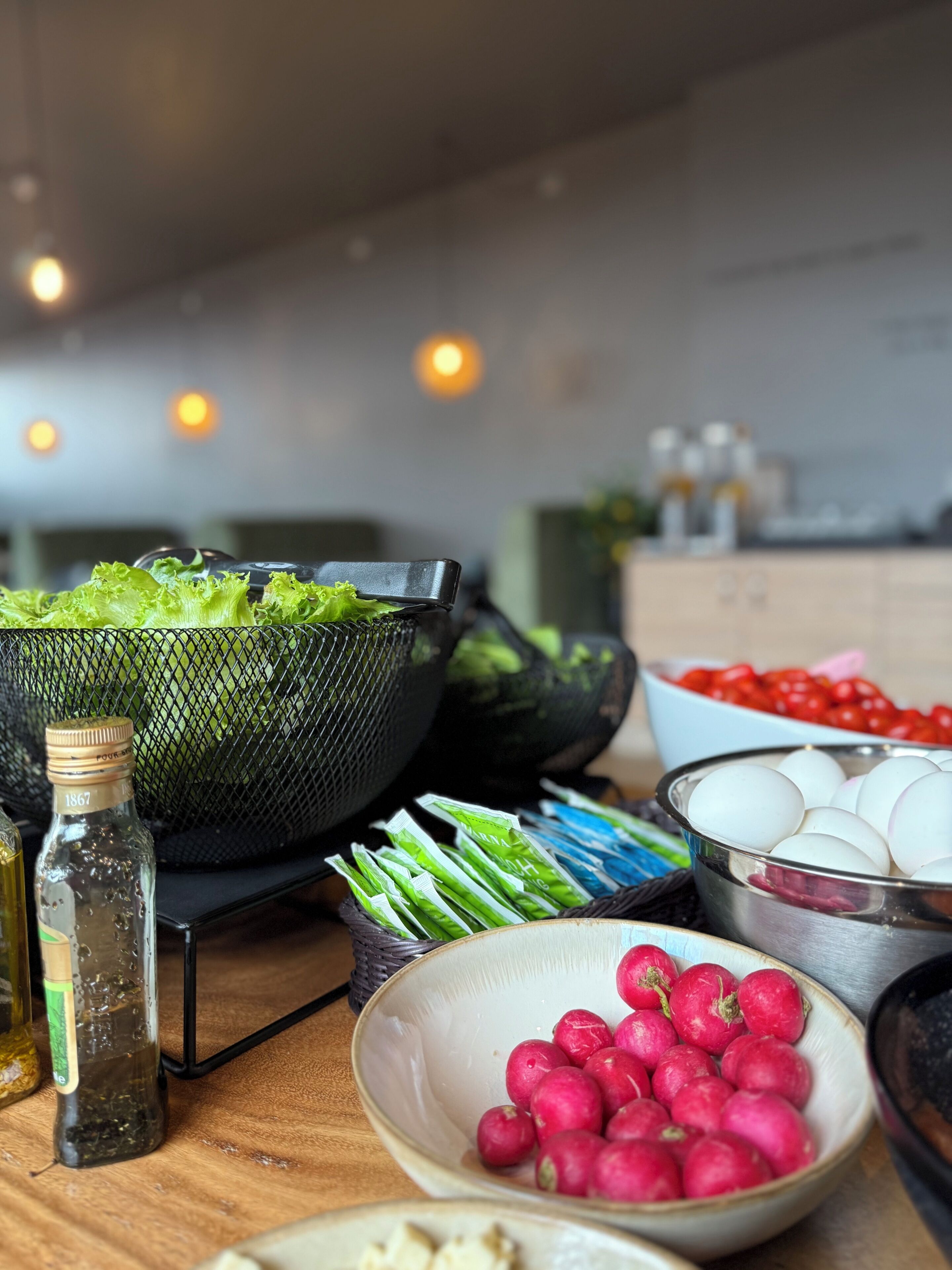 Una encimera de cocina con diversos alimentos, como lechuga, rábanos, huevos y una botella de aceite.