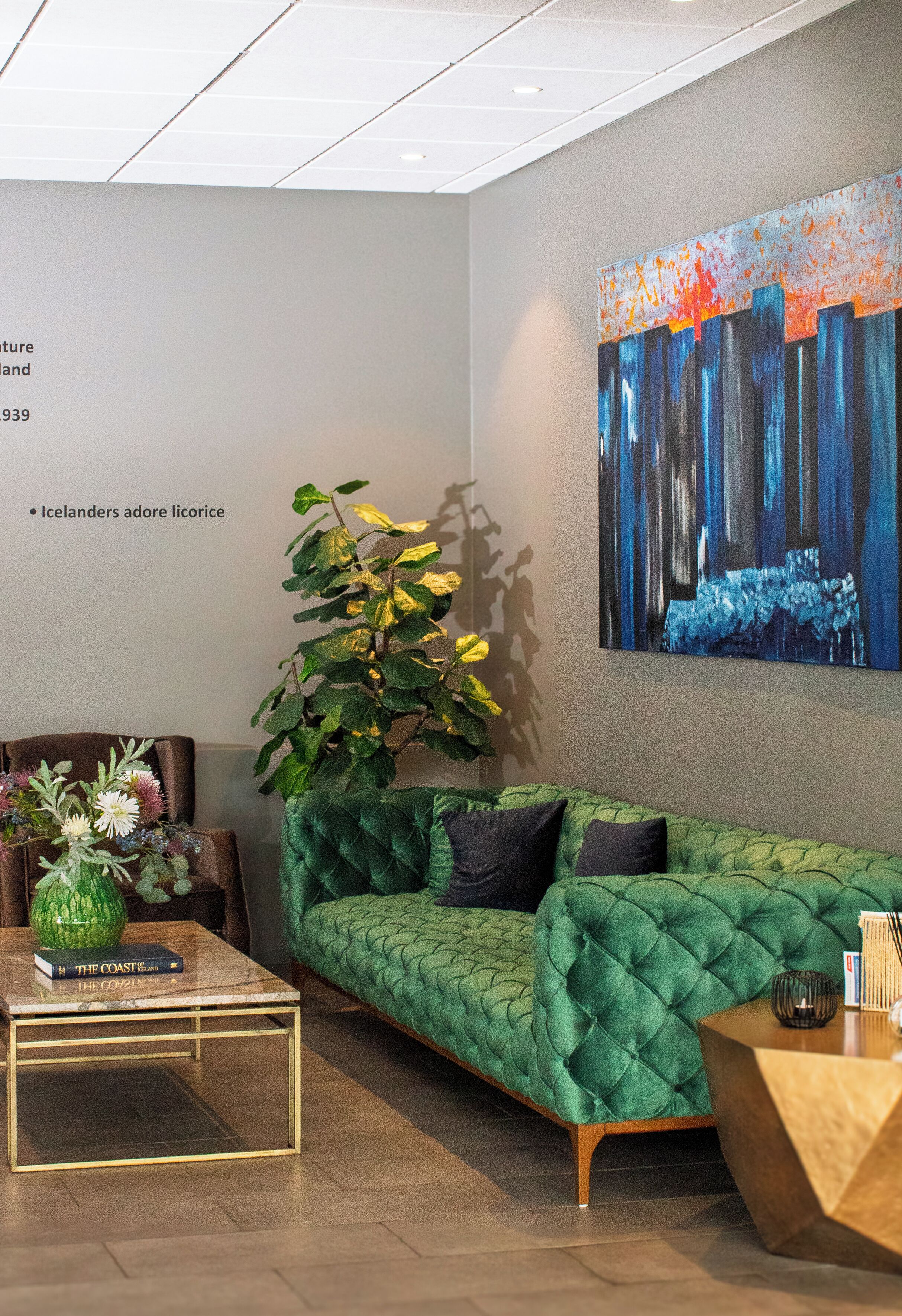 A modern living room with a green sofa, a coffee table, and a painting on the wall.