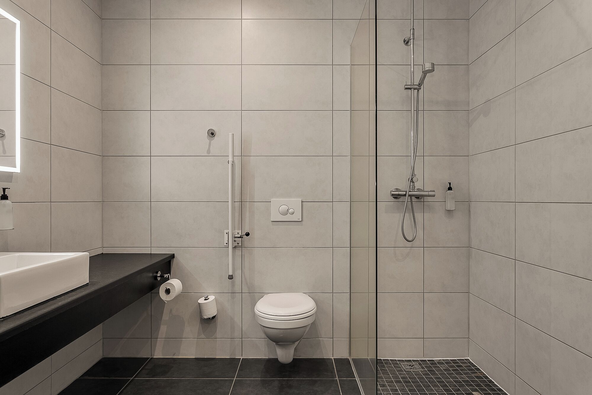 A modern bathroom with a toilet, a shower, and a sink.