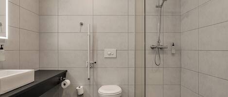 A modern bathroom with a toilet, a shower, and a sink.