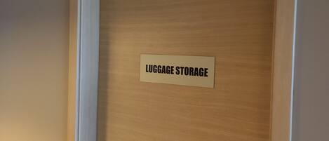 Una puerta de madera con un cartel que dice 'LUGGAGE STORAGE'.