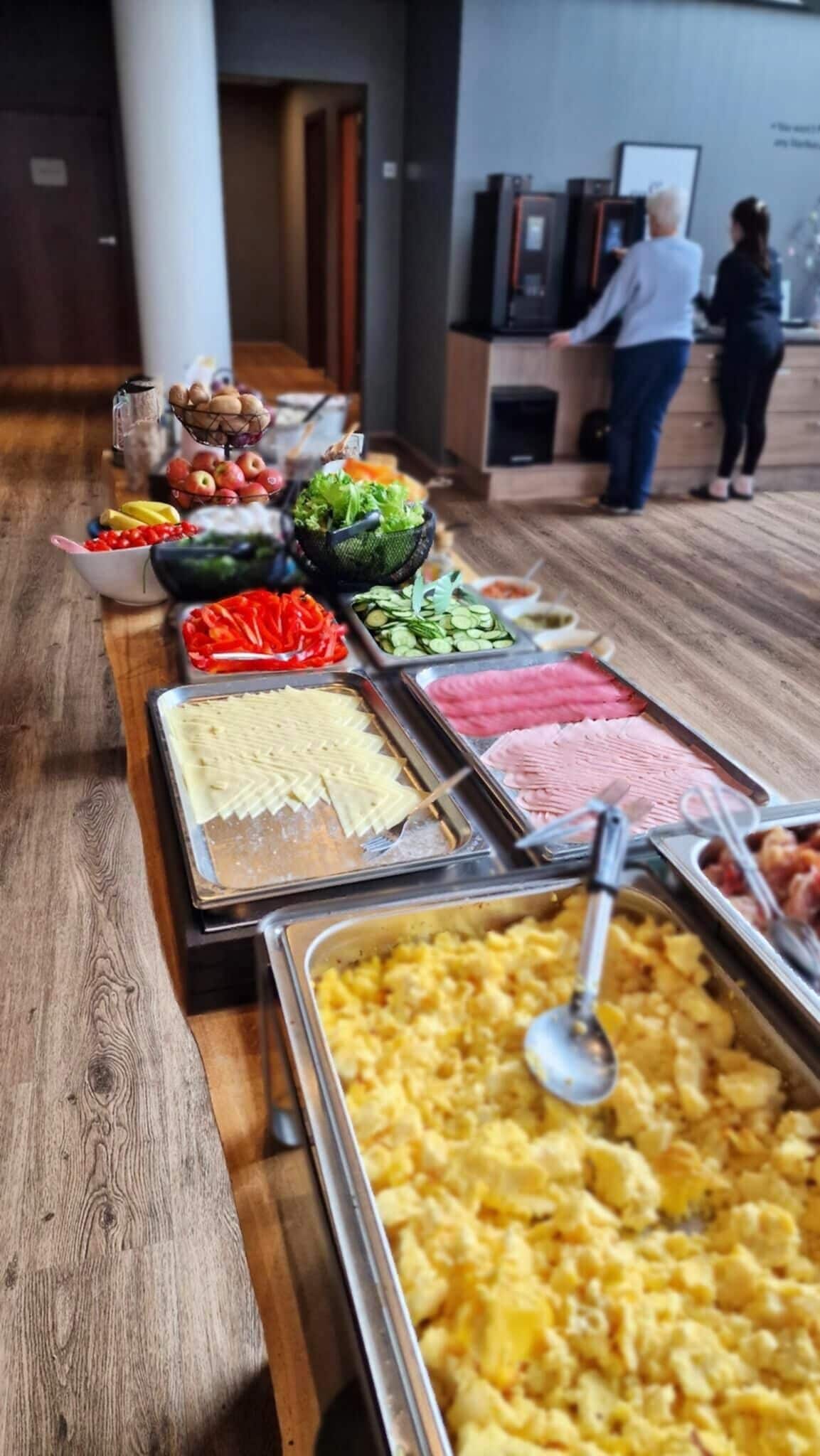 A buffet line with various food items including fruits, vegetables, and meats.